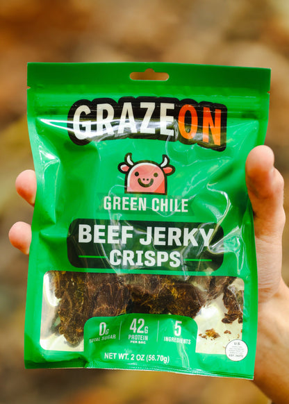 Green package of Graze On Green Chile Beef Jerky Crisps held in a hand with a blurred natural background