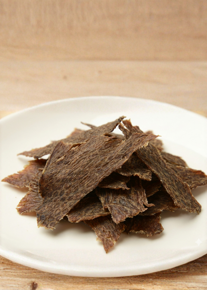 Dried beef jerky on a white plate with a wooden background